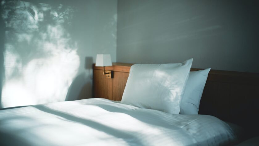 white bed linen beside brown wooden nightstand